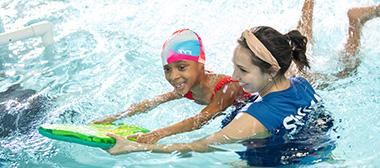 A child learning water safety with a YMCA instructor