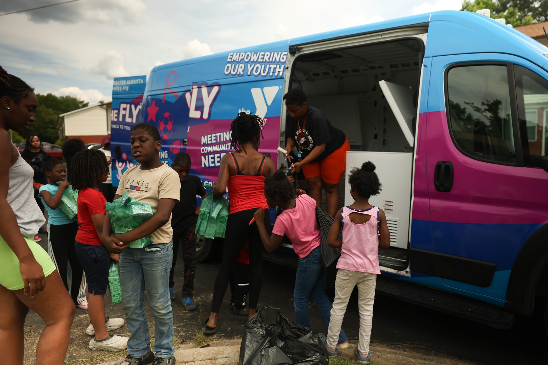 Children receiving food pantry bags from the Y on the Fly van